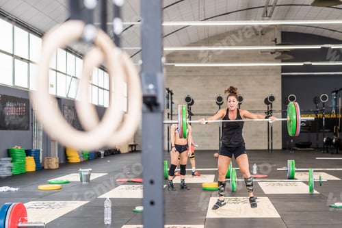 Preview: young woman indoors gym cross training power lifting