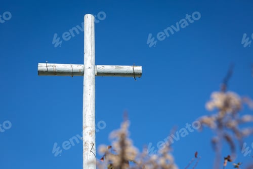 Preview: Wooden cross stands against a vivid blue sky with a blossoming tree in the foreground
