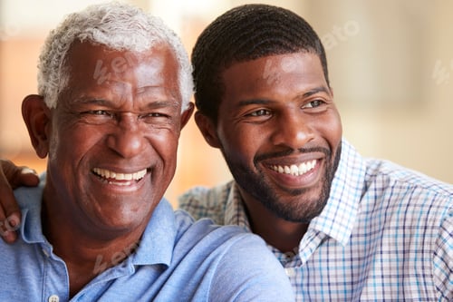 Preview: Smiling Senior Father Being Hugged By Adult Son At Home