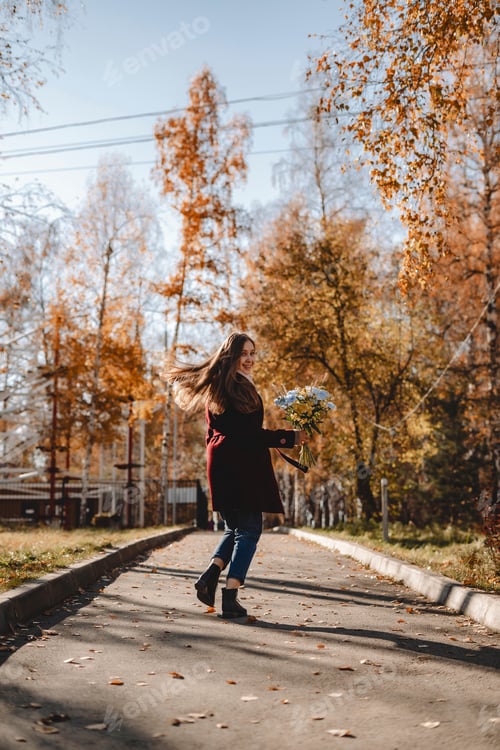 Preview: Woman with bouquet of flowers in an autumn park