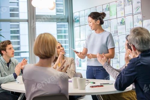 Preview: Female digital designer explaining ideas to team at conference table