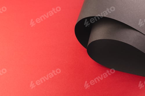 Preview: Close up of rolled up pieces of black paper with copy space on red background