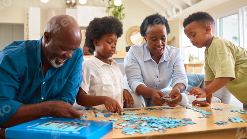 Preview: Grandparents With Grandchildren Indoors Sitting Around Table At Home Doing Jigsaw Puzzle Together
