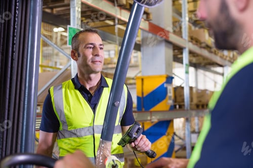 Preview: Supervisor instructing male forklift truck driver in distribution warehouse