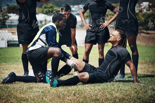 Preview: Cropped shot of a young rugby player receiving first aid assistance on the field