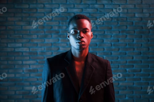 Preview: Futuristic neon lighting. Young african american man in the studio