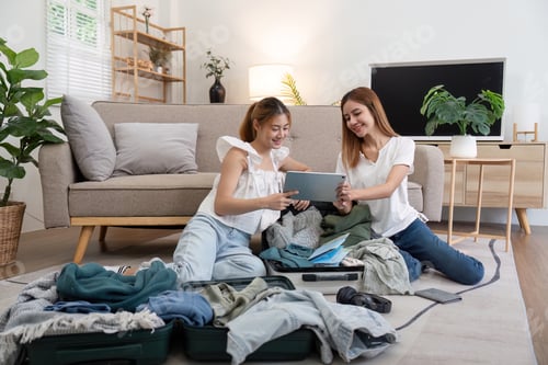 Preview: Young Asian woman packing clothes to the suitcase. Preparation for the summer vacation. Two women