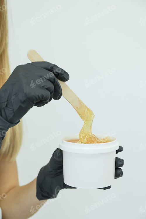 Preview: Woman holding liquid yellow paste for shugaring against white background, copy space