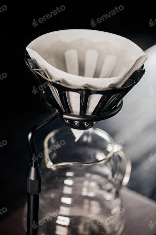 Preview: close up view of coffee filter bag in dripped stand above glass coffee pot, V-60 style brew method