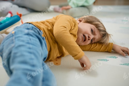Preview: Sad little boy crying while lying down on floor.
