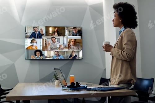 Preview: African American Businesswoman Looking At Projection Screen While Talking To Group Of Coworkers