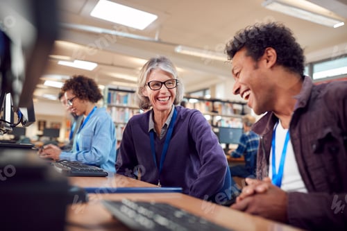 Preview: Teacher With Group Of Mature Adult Students In Class Working At Computers In College Library