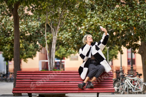 Preview: Woman making selfie holding phone in city park