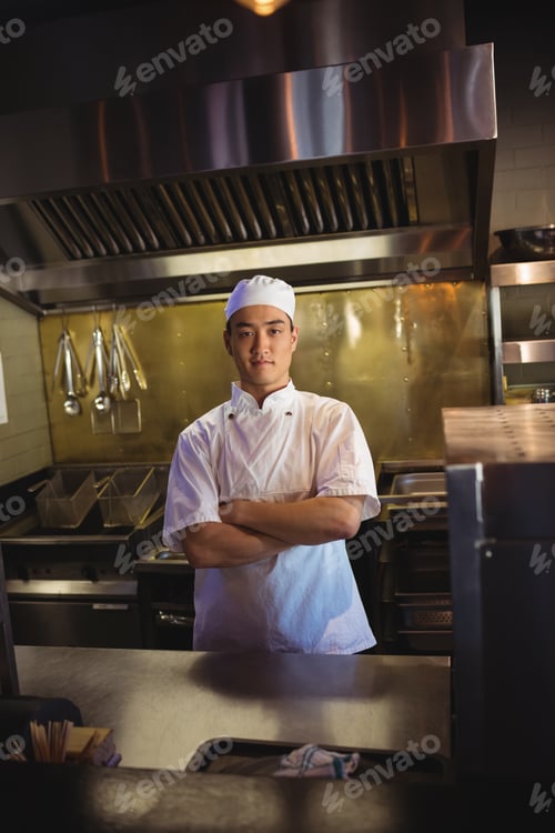 Preview: Smiling chef standing with arms crossed in the commercial kitchen