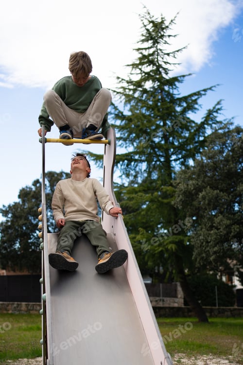 Preview: Children having fun on slide in playground during summer day