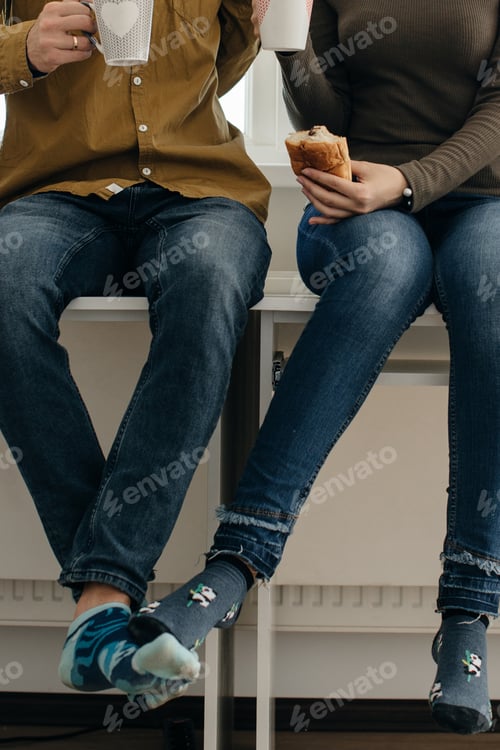 Preview: Couple wearing funny socks enjoying coffee and pastry during break time