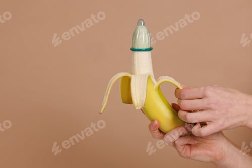 Preview: A woman's hand shows how to put a condom on the penis using a banana as a demonstration