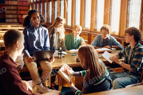 Preview: Happy black teenager girl using laptop while studying with friends in library.