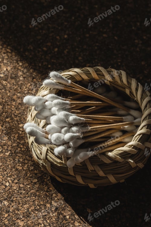 Preview: Wooden Cotton Swabs in Woven Basket on Cork Surface