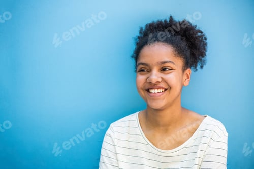 Preview: Close up horizontal African American girl smiling and looking away by blue background