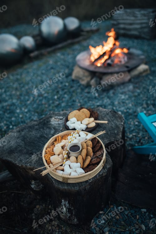 Preview: Marshmallows for roasting on a tray with campfire on the background.