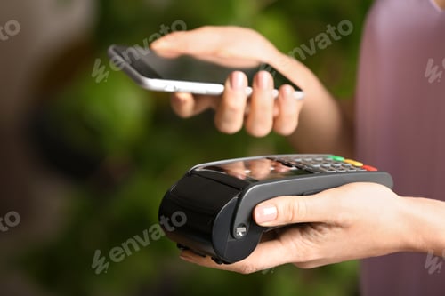 Preview: Woman using modern payment terminal with mobile phone indoors, closeup