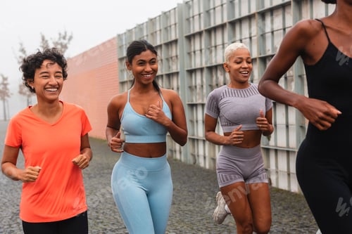 Preview: Four sportswomen running together in the city during training