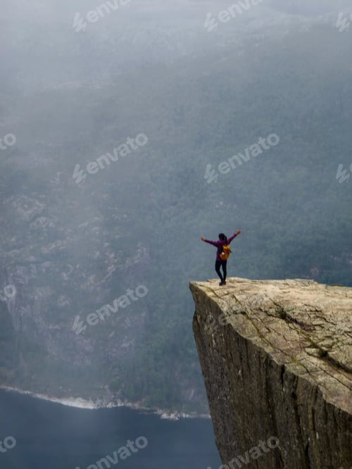 Preview: A Bold Climber Embraces Nature on the Edge of Preikestolen in Norway's Mystical Twilight