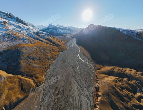 Preview: Bright sun over a glacial river in a panoramic mountain valley