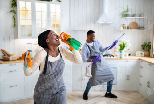 Preview: Happy black lady using detergent as microphone, her boyfriend playing mop like guitar at kitchen