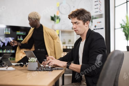 Preview: Side view of focused caucasian man working on laptop