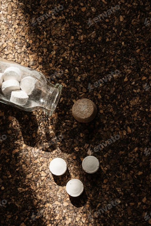 Preview: Glass Jar with Spilled Toothpaste Tablets on Cork Surface