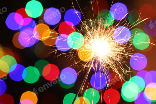 Preview: Bright burning sparkler on dark background with blurred lights, space for text. Bokeh effect