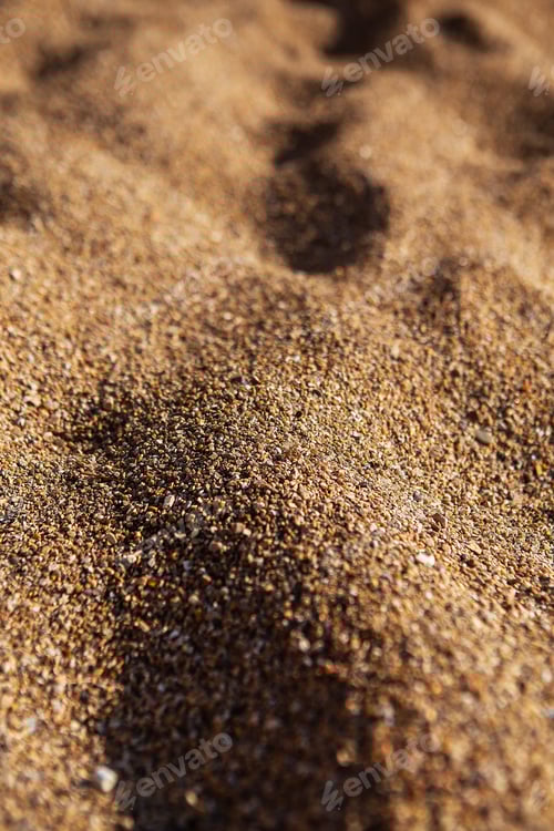 Preview: The texture of sand and small pebbles close up. Sun shadows, warm light.