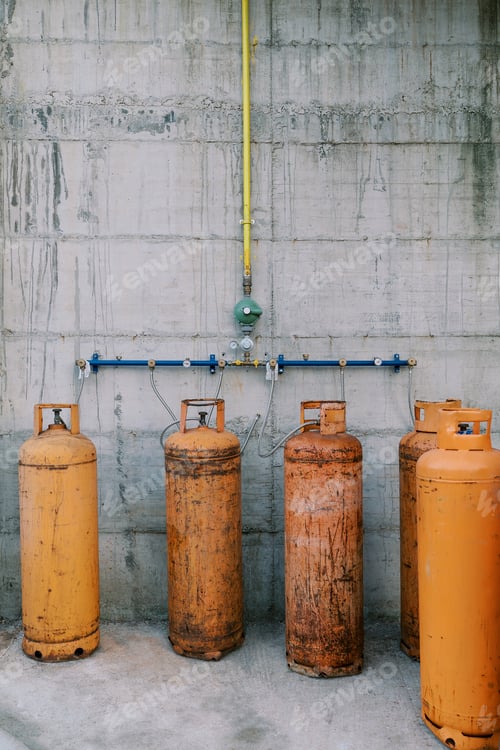 Preview: Orange gas cylinders connected to pipes on a concrete wall