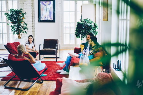 Preview: Young hipsters discussing plans for weekends during socialising meeting in comfortable home interi