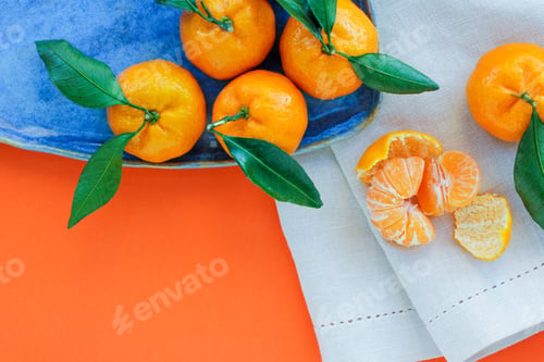 Preview: Tangerines with leaves in a blue plate on an orange background. A symbol of Christmas food