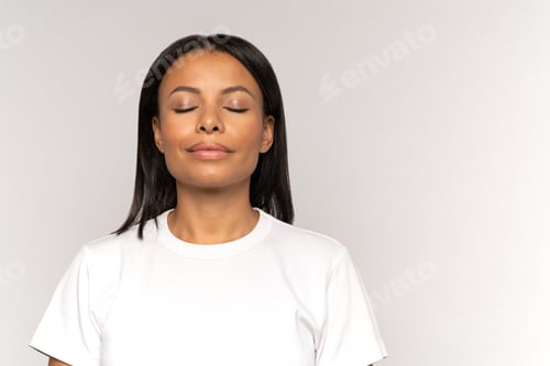 Preview: Peaceful young woman with closed eyes and relaxed smile breathing deeply practice positive thinking