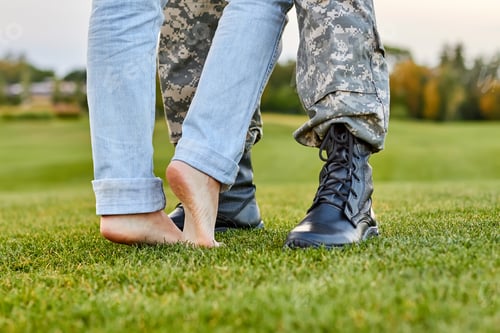 Preview: Close up soldier boots and girlfriend with naked feet.