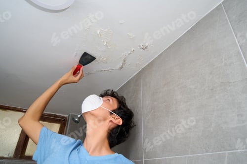 Preview: Young man fixing damp and saltpeter problem on the wall and ceiling