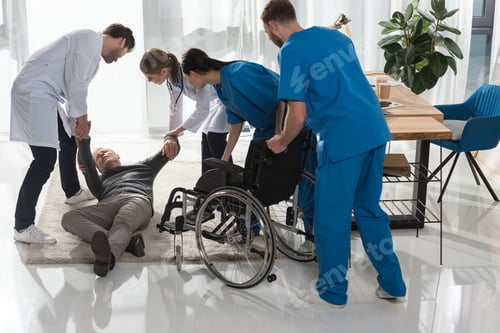 Preview: doctors helping fell mature man to sit on wheelchair