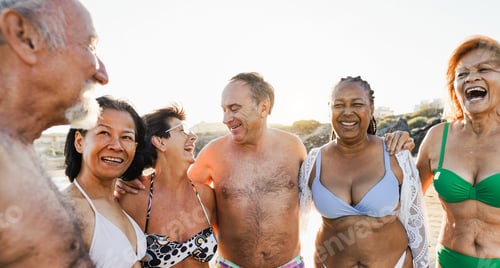 Preview: Senior multiracial friend wearing swimsuit while walking on the beach