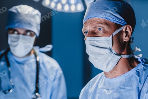 Preview: Concentrated surgeon performing surgery with his team in hospital operating room.