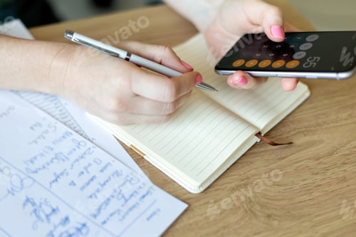 Preview: Woman making audit of household spendings at home using calculator on her mobile phone