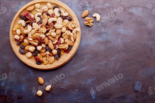 Preview: Aesthetic wooden bowl with assorted nuts, raisins and cranberries from above on rustic background.
