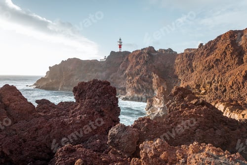 Preview: Rocky ocean coast with lighthouse on a sunset