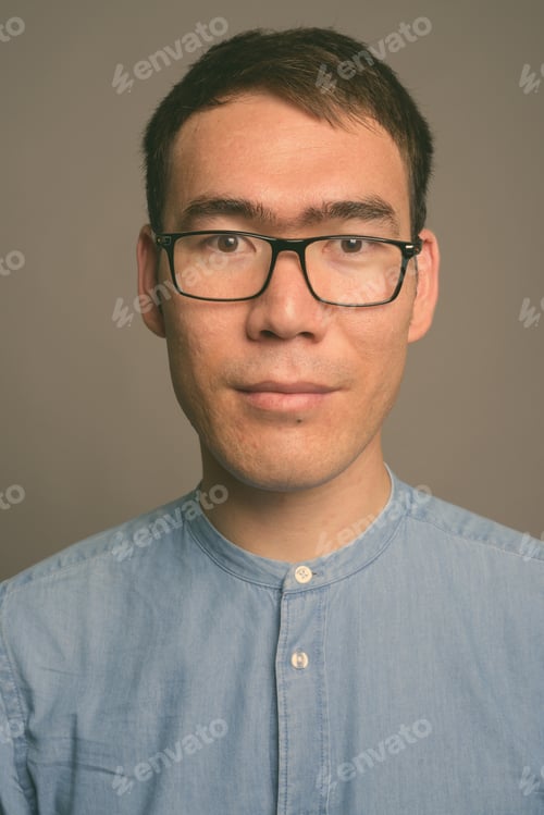 Preview: Young Asian businessman against gray background