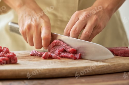 Preview: Unrecognizable woman cutting meat on board