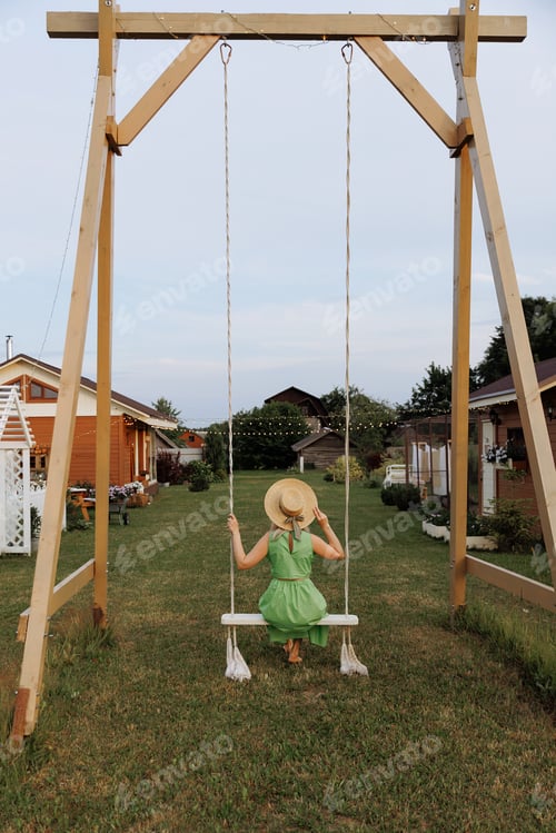 Preview: Blonde woman swinging in green dress. Back view.