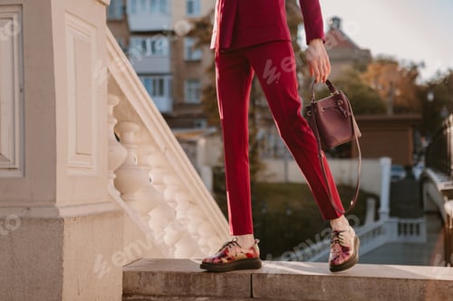 Preview: beautiful stylish woman in purple suit and hat walking in city street